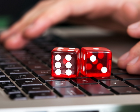 Close-up of red game dices on laptop with hands in background