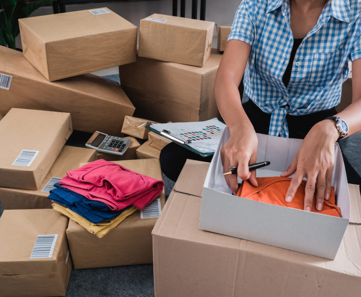 Young woman packing of clothes on the boxes to be shipped in her office
