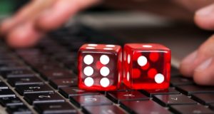 Close-up of red game dices on laptop with hands in background